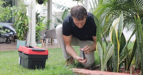Plumber Man fixing Sprinkler Head in backyard Stock Footage 120670358
