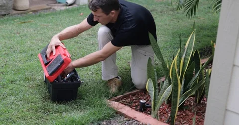 Plumber Man fixing Sprinkler Head in backyard Stock Footage 120670371
