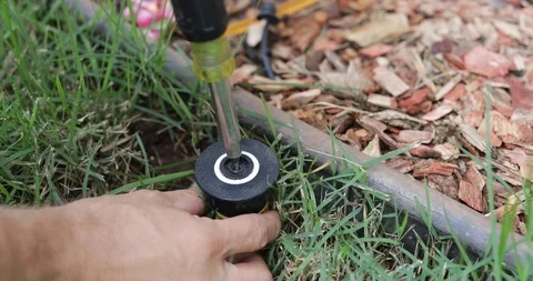 Plumber Man fixing Sprinkler Head in backyard Stock Footage 120670402