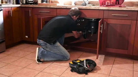 Plumber man with tools in the kitchen. Plumbing and renovation Stock Footage 71837279
