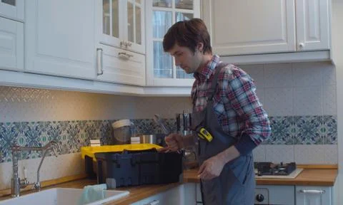 Plumber opens tool box in the kitchen Stock Photos