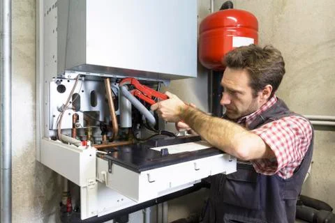 Plumber repairing a condensing boiler Stock Photos