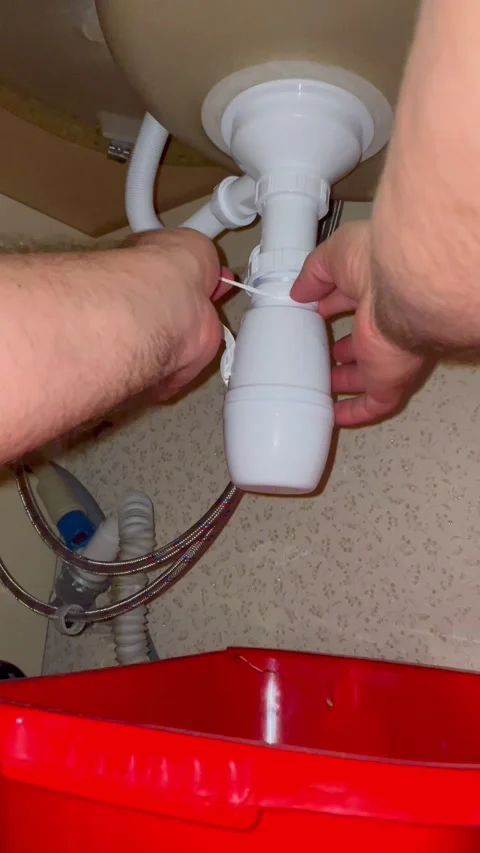 Plumber repairing kitchen sink pipe. Man fixing drain trap under basin. Stock Footage 340124697