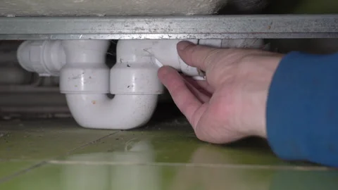 Plumber repairing a plastic siphon under the bathtub close-up Stock Footage 337695863