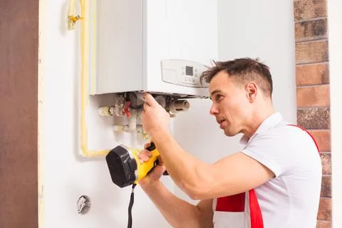 The plumber repairs a boiler at the kitchen Stock Photos