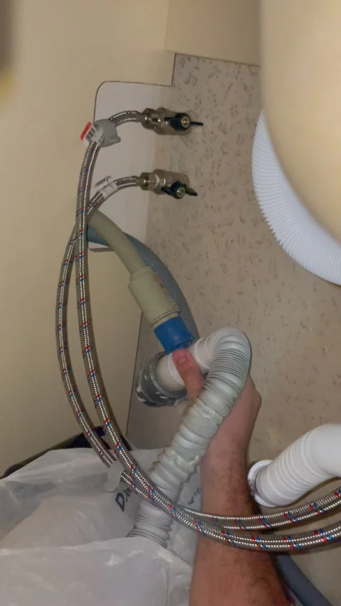 Plumber replaces drain pipe of kitchen sink. Man connects flexible hose to Stock Footage 340124714