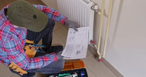 Plumber reviews schematic by toolbox and checks part numbers Stockbeeldmateriaal 322009629