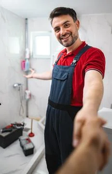 Plumber shaking hands with customer after finishing work in bathroom Stock Photos