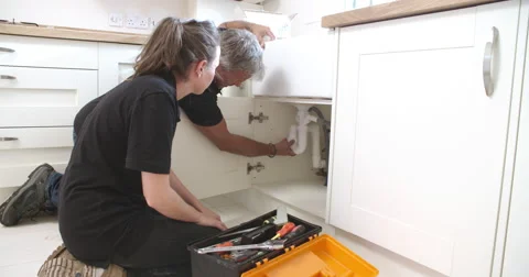 Plumber showing female apprentice how to fit a kitchen sink Video stock 56216944