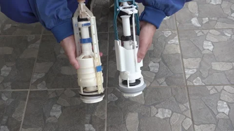 A plumber shows old and new drain valves for a toilet Stock Footage 329012749