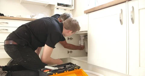 Plumber teaching apprentice to fix kitchen sink Stock Footage 56217933