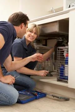 Plumber Teaching Apprentice To Fix Kitchen Sink In Home Stock Photos