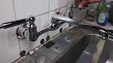 Plumber testing out new faucet and letting water run with rust Stock Footage 249923988