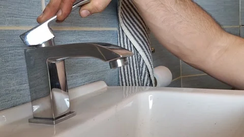 A plumber tests the function of a faucet. A plumber's hands checking a water tap 스톡 동영상 266443912