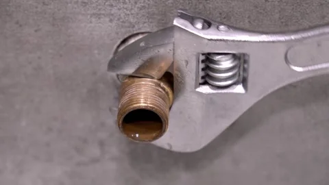 Plumber tightening brass pipe fitting with adjustable wrench Stock Footage 304118514