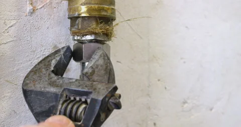 Plumber tightening a nut on a pipe with an adjustable wrench Stock Footage 302339450