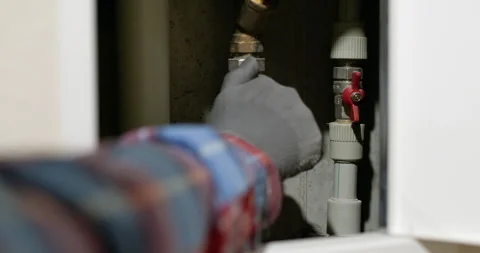 Plumber turns tap to adjust flow of water in plumbing system Video stock 247171315