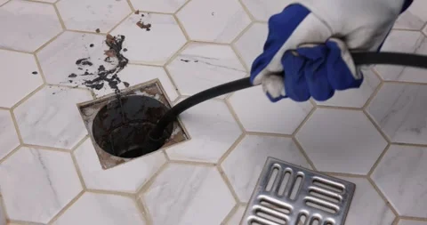 Plumber unclogging blocked shower drain with hydro jetting at home bathroom.. Stock Footage 305167717