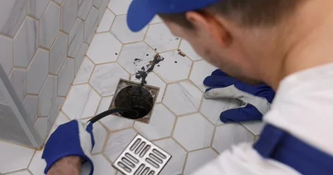 Plumber unclogging blocked shower drain with hydro jetting at home bathroom.. Stock Footage 305167735