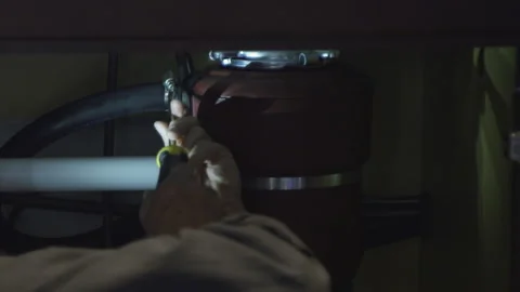 Plumber under kitchen sink fixing garbage disposal Stockbeeldmateriaal 277018609