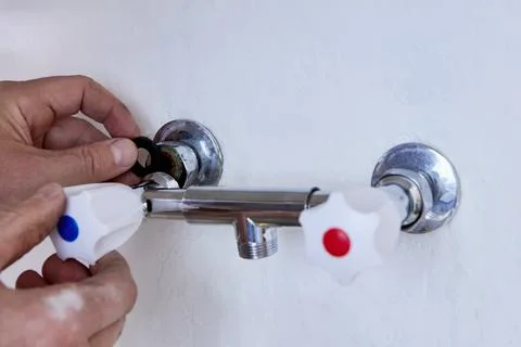 Plumber uses both hands to position black rubber gasket on threaded pipe be.. Stock-Fotos