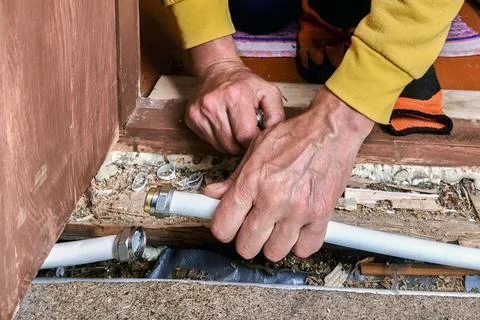 Plumber uses hands to connect multilayer pipe with compression fitting, wor.. Stock Photos