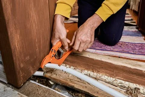 Plumber uses pipe cutter to remove leaking section from plastic tubing duri.. Foto stock