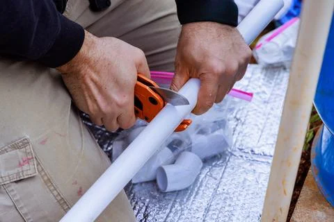 Plumber uses special scissors when installing plastic PVC a water pipes Stock Photos