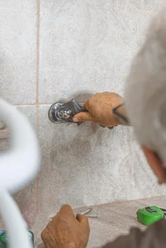 Plumber using an adjustable wrench to tighten plumbing connections during wa 库存照片