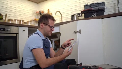 Plumber using a digital tablet in the kitchen Stock Footage 321893880
