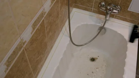 Plumber using a plunger to clear a clogged bathtub drain, showcasing the action Stock Footage 326496136
