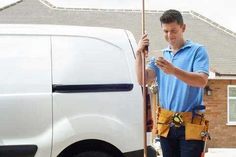 Plumber With Van Using Mobile Phone Outside House Stock Photos