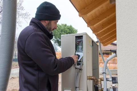 Plumber at work installing a heat pump Stock Photos