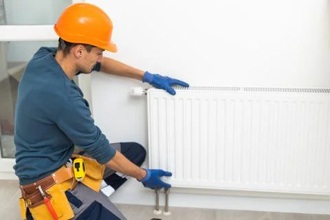 Plumber at work. Installing water heating radiator Stock Photos