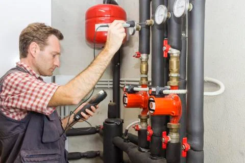 Plumber at  work measures the temperature in a boiler room Foto stock