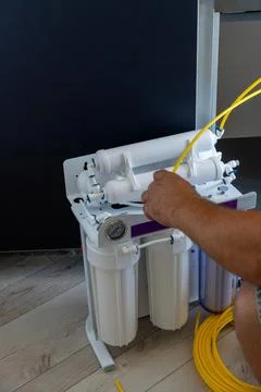 Plumber worker assembling water filtration system with yellow tube Fotos de archivo