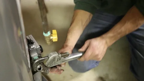 Plumber Working on Job Site Wrenching Fitting on Water Heater Stock Footage