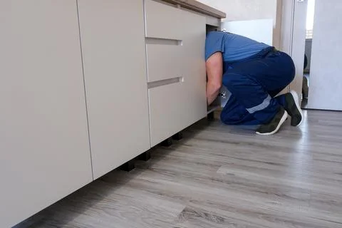 Plumber working on a kitchen sink, performing maintenance and repair servic.. Stock Photos