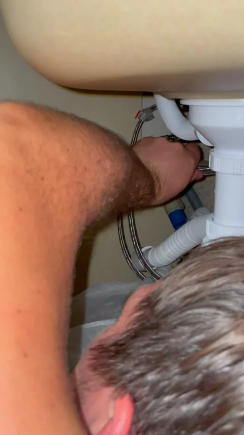 Plumber works under kitchen sink connecting metal pipe to water supply. Stock Footage 340124712