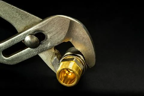 Plumber wrench with brass fitting on dark background. Plumbing repair idea Stock Photos
