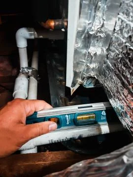 Plumbers hand using a level to pitch HVAC pvc piping. Stock Photos