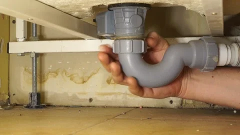 The plumber's man's hand unclogs the drain under the tub. The man pulls out a Stock Footage 144729490