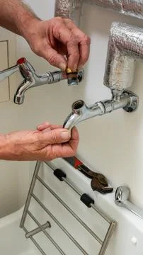 Plumbing contractor inspecting a ceramic insert on a tap on a butler sink. 写真素材