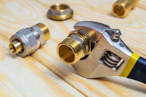 Plumbing fitting and adjustable spanner on wooden boards during repair or rep Stock Photos