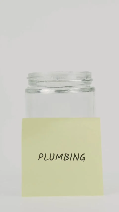 Plumbing text or word on yellow sticky note attached to glass jar with hand Stock Footage 311768649