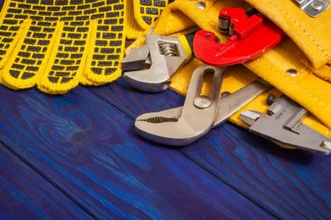 Plumbing tools in the bag and work gloves on blue wooden boards are used to r Stock Photos