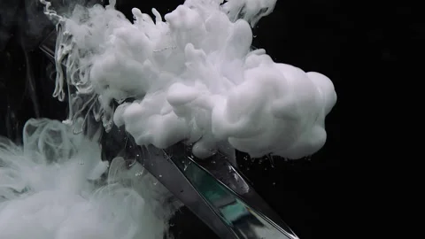 Plumes of thick white smoke flow down along a silver cover on a black background Stock Footage 267454076