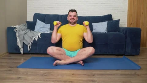 Plump man is doing physical exercise for weight loss. Sits on sports mat and Stock Footage 170607927