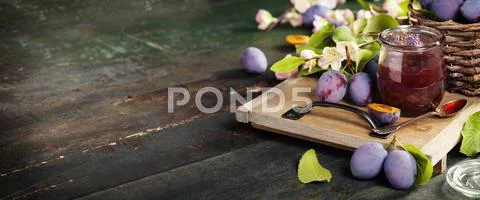 Plums and jar of jam on table Stock Photos
