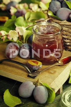 Plums and jar of jam on table Stock Photos